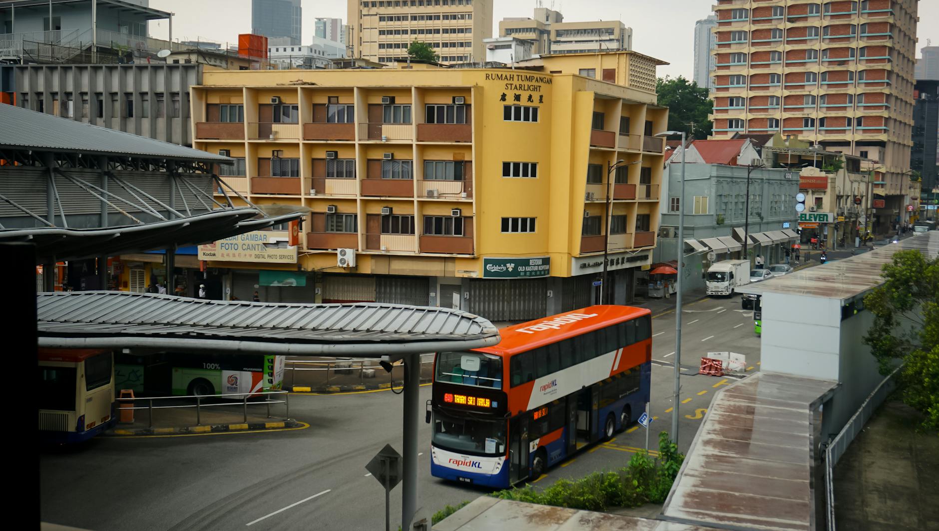 Malezyjskie transportowe ciekawostki: łodzie rzeczne, minivany, pociągi i lokalne promy Autobusy na ruchliwej ulicy Kuala Lumpur na tle nowoczesnych wieżowców