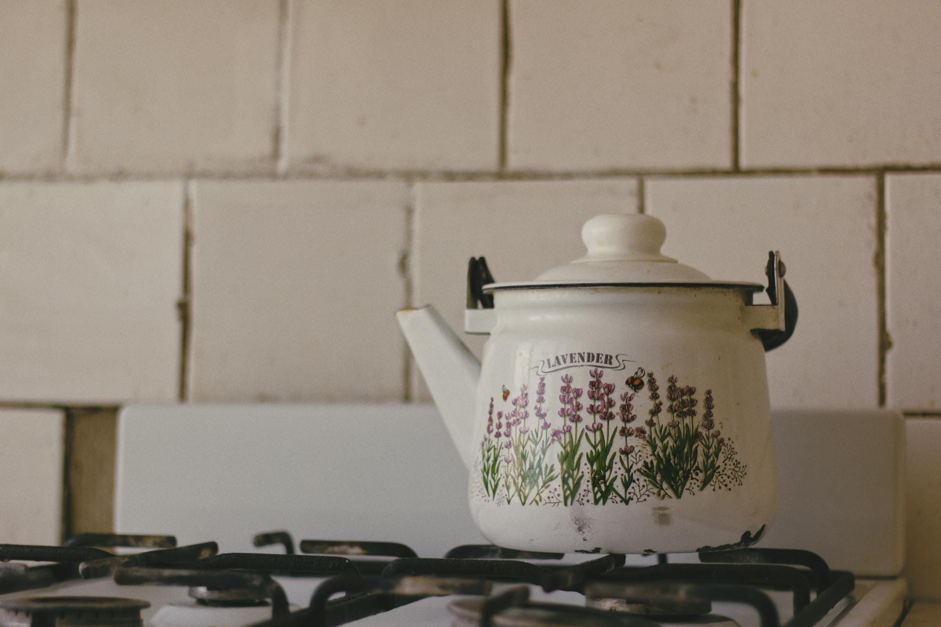 Emaliowany czajnik w kwiaty lawendy stojący na kuchence gazowej