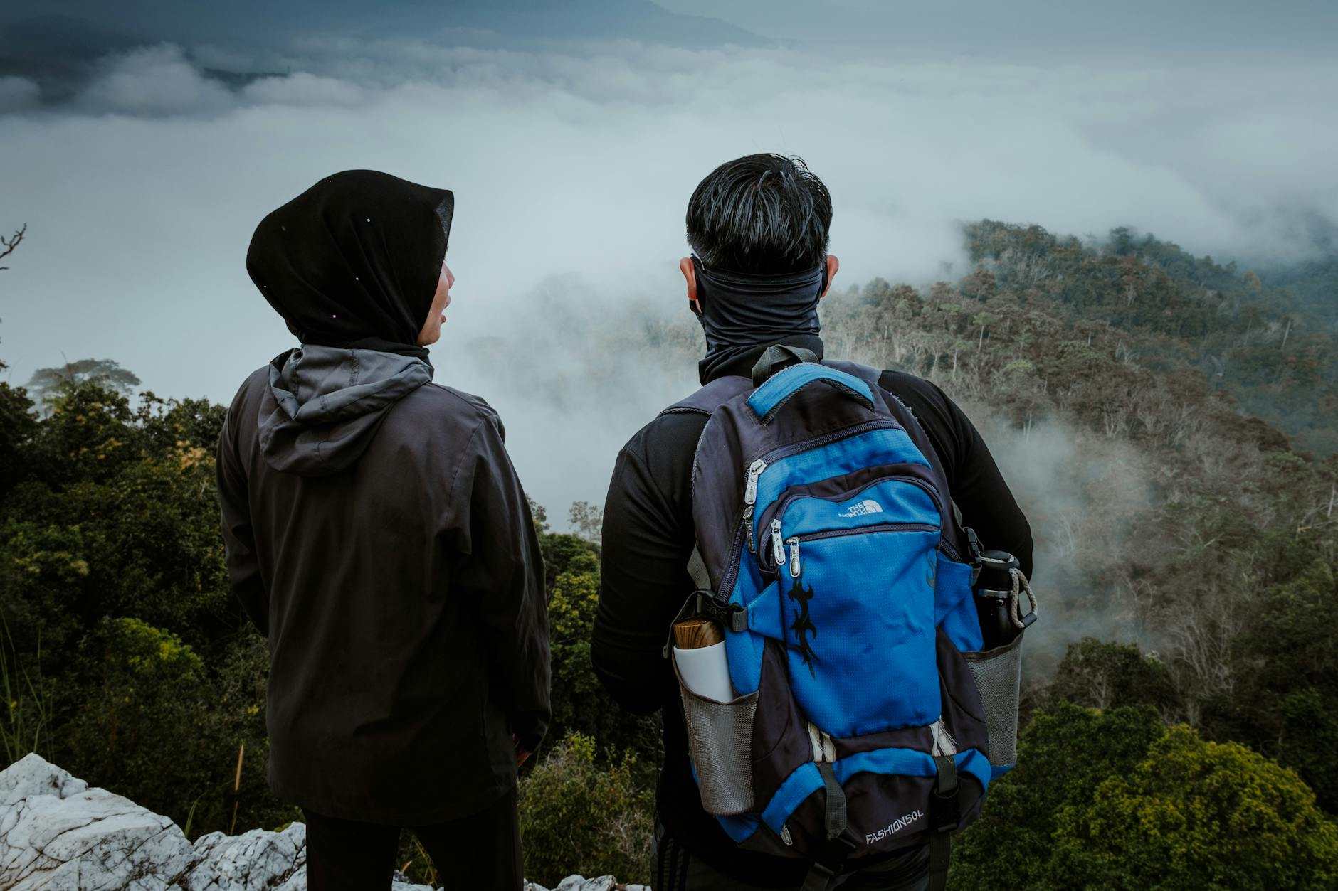Dwóch turystów na klifie podziwia mglisty las w Malezji