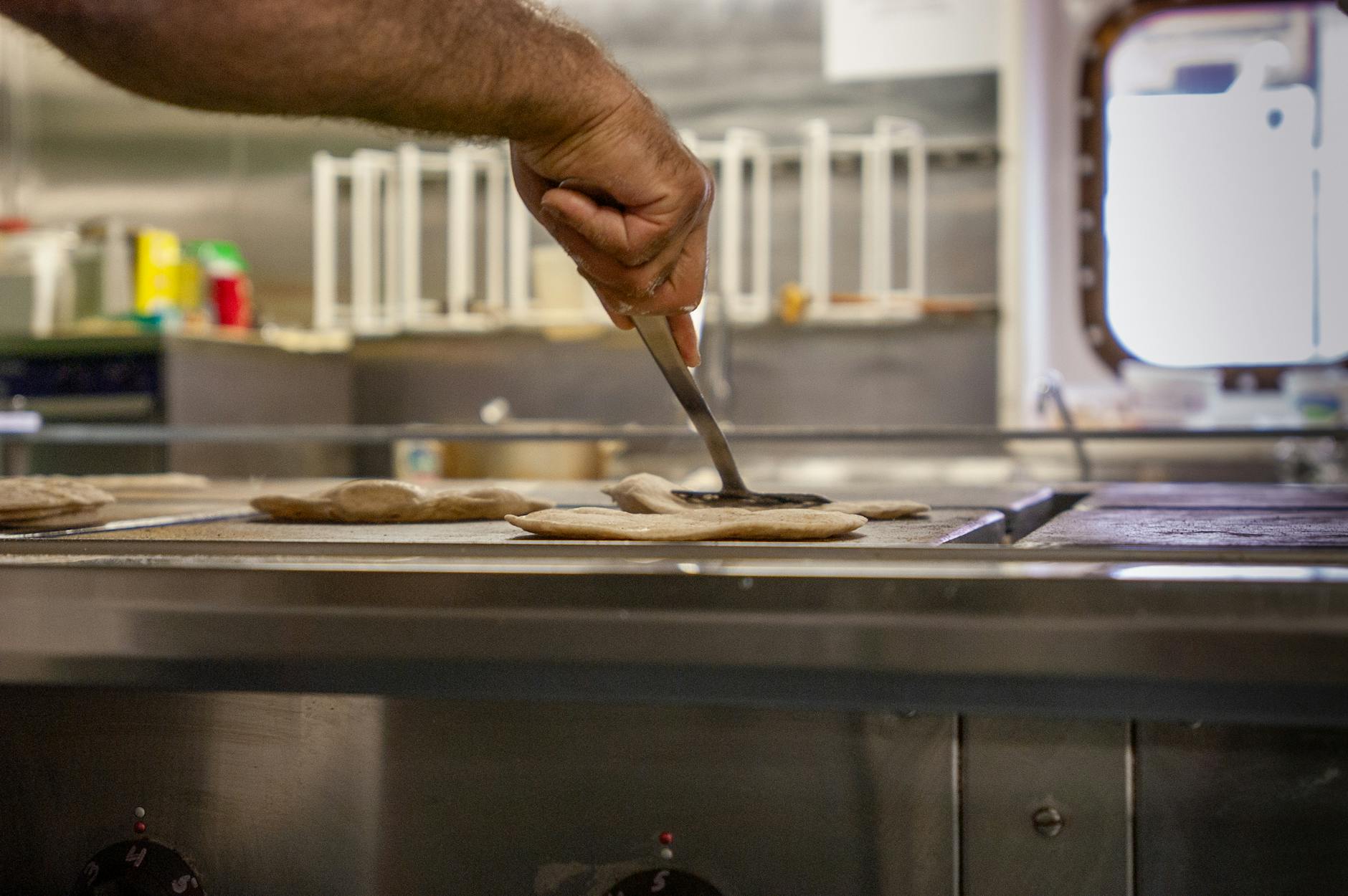 Kucharz formuje roti canai na rozgrzanej płycie w kuchni statku